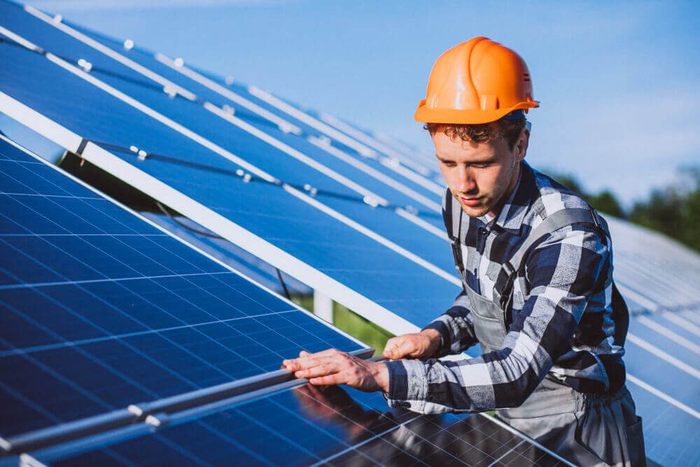 Homem de capacete laranja trabalhando em painéis solares