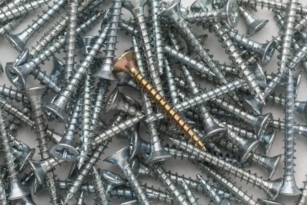 Vários parafusos de inox esparramados por uma superfície branca.