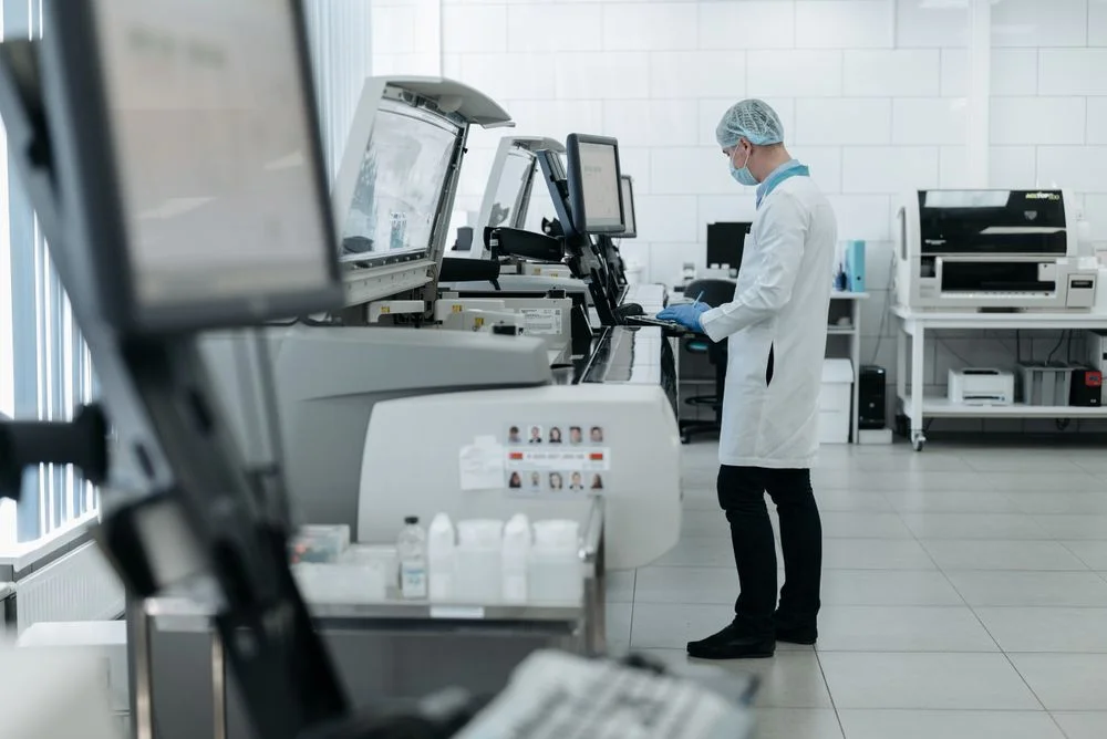 Um cientista em um jaleco usando equipamentos laboratoriais avançados em um laboratório limpo e moderno, representando a análise química dos fixadores de inox.